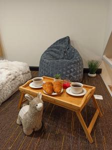 uma mesa de café com croissants, chávenas e um bicho de peluche em Tiny House em Narva-Jõesuu