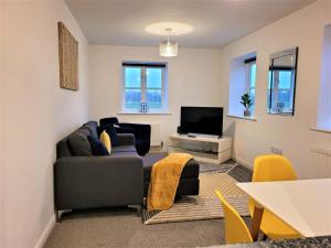 a living room with a couch and a tv at Catchpole Stays Abbey Field Apartment- A lovely 2 bed apartment with field views near Colchester town centre in Colchester