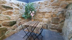einen Holztisch und eine Bank mit Blumen in einer Steinmauer in der Unterkunft Seasons Porto-Gaia by MyStay in Vila Nova de Gaia