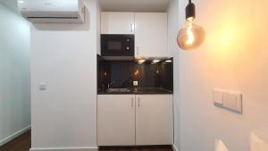 a white kitchen with a sink and a microwave at Seasons Porto-Gaia by MyStay in Vila Nova de Gaia