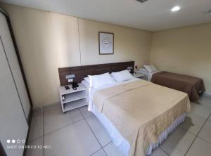 a hotel room with two beds and a night stand at Flat espaçoso na orla de Tambaú - Nobile Suítes in João Pessoa +12 photos