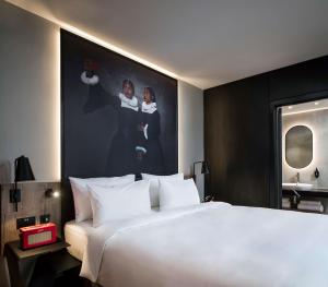 a large white bed in a hotel room with a painting at Radisson RED Hotel, Liverpool in Liverpool