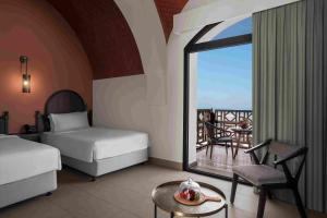 a bedroom with two beds and a view of a balcony at The Cove Rotana Resort - Ras Al Khaimah in Ras al Khaimah