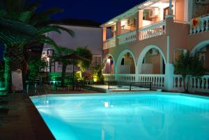 a swimming pool in front of a building at night at Eugenia Hotel & Apartments in Laganas