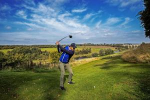 una mujer golpeando una pelota de golf con un palo en SCHLOSS Roxburghe, part of Destination by Hyatt, en Kelso