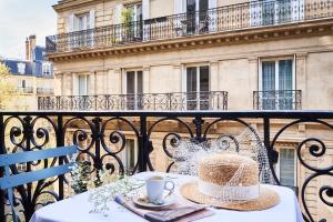 - une table avec un chapeau et une tasse de café sur le balcon dans l'établissement Hôtel Sainte-Beuve, à Paris