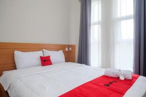 1 dormitorio con cama blanca y manta roja en RedDoorz Syariah near Universitas Tidar Magelang, en Magelang