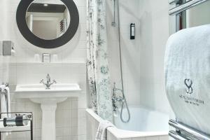 bagno bianco con lavandino e doccia di Hôtel Sainte-Beuve a Parigi