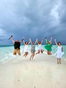 un grupo de personas saltando al aire en la playa en Serene Sky Guest house en Thoddoo