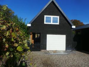 una casa negra con una puerta de garaje blanca en Top appartement Short Stay in mooie omgeving Kortenhoef., en Kortenhoef