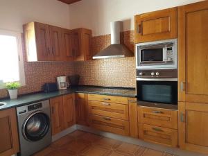 cocina con armarios de madera, lavadora y microondas en Apartamento rural zona céntrica isla en Puerto del Rosario