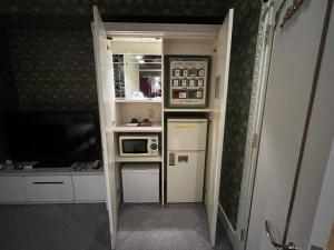 eine kleine Küche mit einer Mikrowelle und einem Kühlschrank in der Unterkunft Hotel Pharaoh-Adult Only in Sapporo