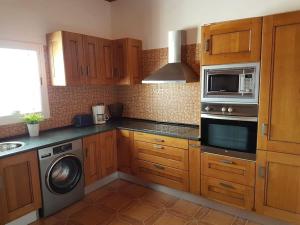 a kitchen with wooden cabinets and a microwave at Apartamento rural zona céntrica isla in Puerto del Rosario