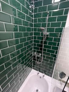 a green tiled bathroom with a sink and a shower at Hoole House- Recently decorated, bright and modern 2 bedroom house, close to Chester train station and the City Centre in Chester