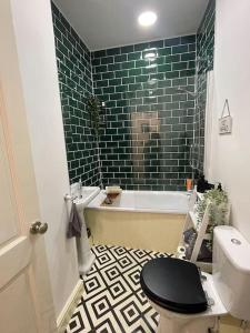 a bathroom with a black toilet and a tub and a sink at Hoole House- Bright and modern 2 bedroom house, close to Chester train station and the City Centre in Chester