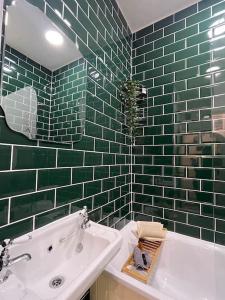 W wyłożonej zielonymi kafelkami łazience znajduje się wanna i umywalka. w obiekcie Hoole House- Bright and modern 2 bedroom house, close to Chester train station and the City Centre w mieście Chester
