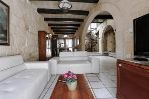 a living room with white couches and a tv at Ta'Peppa in Xagħra