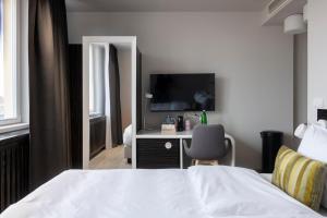 - une chambre avec un lit et un bureau avec une télévision dans l'établissement numa I Poise Rooms & Apartments, à Prague