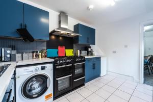 a kitchen with blue cabinets and a washing machine at Jesouth Homey 5 Bedrooms 9 Beds - Contractors - Leisure - Central Location in Hull