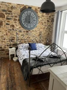 a bedroom with a large clock on a brick wall at Honestone Street hideaway in blissful Bideford in Bideford