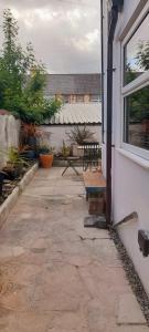 a patio with a bench next to a window at Honestone Street hideaway in blissful Bideford in Bideford