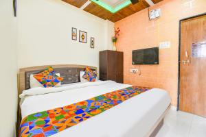 Un dormitorio con una cama con una manta de colores. en FabExpress Vardhan Executive, en Pune