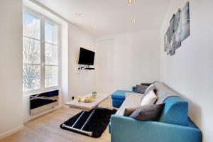 Appartement 4 personnes aux Portes de Paris في سان دوني: غرفة معيشة مع أريكة زرقاء وطاولة
