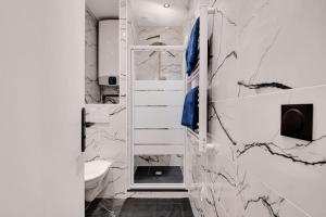 a bathroom with white marble walls and a toilet at Appartement 4 personnes aux Portes de Paris in Saint-Denis