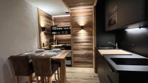 una cocina con armarios de madera y una mesa con sillas. en Les Cerfs - Appartement & Studio - ANZERE, en Anzère