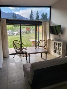ein Wohnzimmer mit einem Sofa, einem Tisch und Stühlen in der Unterkunft El Castaño Apart in Potrerillos