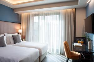 雅典的住宿－Athens Key Hotel, Trademark Collection by Wyndham，酒店客房设有两张床、一张书桌和一个窗户。