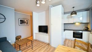 a kitchen and living room with a table and a tv at Apartamenty EverySky Nad Łomnicą 15-15A in Karpacz