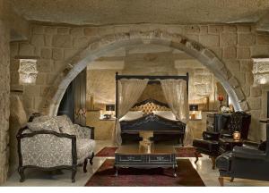 a living room with a bed and a stone wall at Seraphim Cave Suites & SPA in Urgup