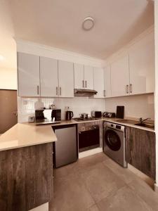 una cucina con armadietti bianchi e lavastoviglie di @Studio102_Sarona a Broadhurst
