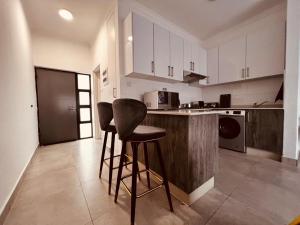 a kitchen with a counter and two stools in it at @Studio102_Sarona in Broadhurst