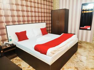 鲁德拉普尔Hotel kingsman的卧室里有一张床，上面有红色和白色的枕头