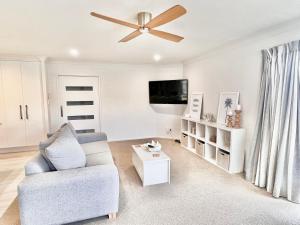 a living room with a couch and a ceiling fan at Home In On Family - 230m from Papamoa Beach in Papamoa