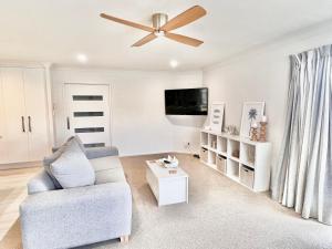 a living room with a couch and a ceiling fan at Home In On Family - 400m from Papamoa Beach in Papamoa