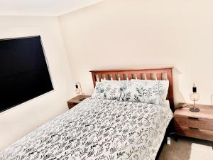 a bedroom with a bed and a flat screen tv at Home In On Family - 230m from Papamoa Beach in Papamoa