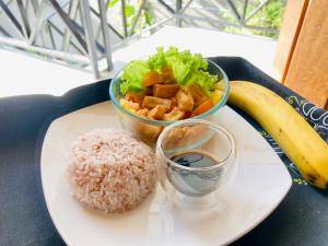 a plate with rice and a bowl of salad and a banana at Balai Lawaan Cozy Homestay in Iloilo City