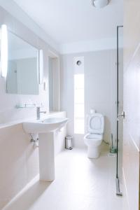 a white bathroom with a sink and a toilet at West Wood Hotel in Nairobi