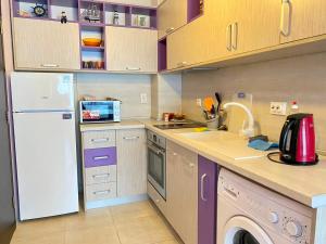 a kitchen with a white refrigerator and a dishwasher at Green Paradise Deluxe Apartments in Primorsko