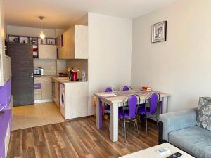 a kitchen with a table and purple chairs in a room at Green Paradise Deluxe Apartments in Primorsko