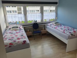 Duas camas num quarto com janelas e uma cadeira em Ferienwohnung Linden em Willich