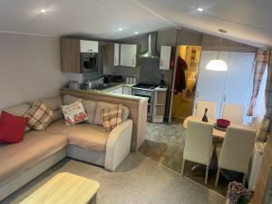 a living room with a couch and a kitchen at The Beeches Holiday Home- based at Aberdunant Hall Holiday Park in Prenteg