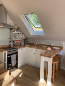 uma cozinha com uma janela, um lavatório e um fogão em The Owl's Nest at Dunkirk Bank em Nailsworth