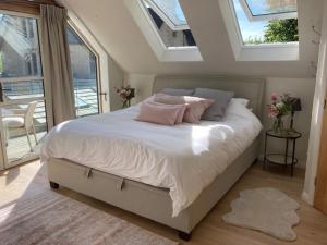 um quarto com uma cama com lençóis brancos e almofadas cor-de-rosa em The Owl's Nest at Dunkirk Bank em Nailsworth