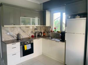a kitchen with white cabinets and a white refrigerator at Luxury Flat of Cleodora Residence in Serik