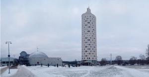 a tall building in the snow next to a building at Wilde Guest Apartment Tigutorn in Tartu