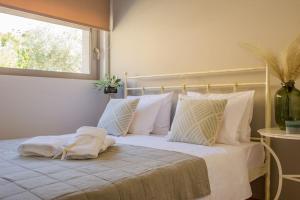 a bedroom with a bed with white pillows and a window at Ether Villa in Theologos